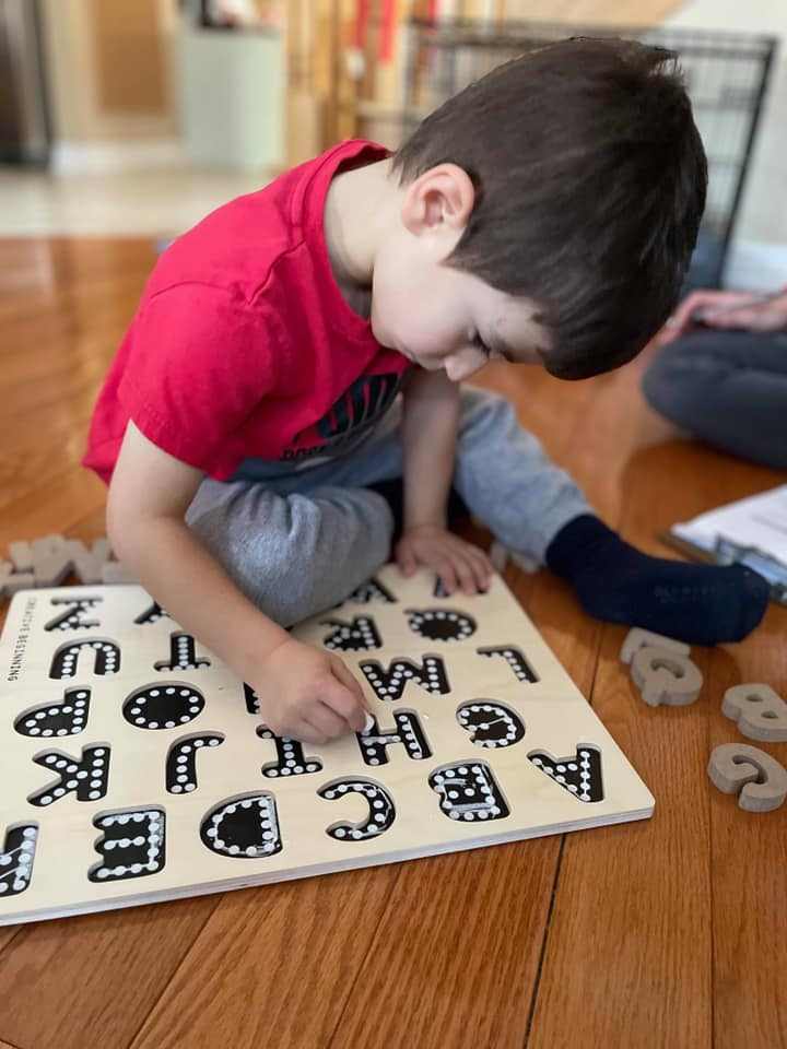 Child playing with alphabetical puzzle on chalkboard base with tracers educational toy
