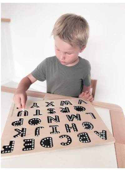 Child using alphabetical puzzle with chalkboard base and tracers for educational learning