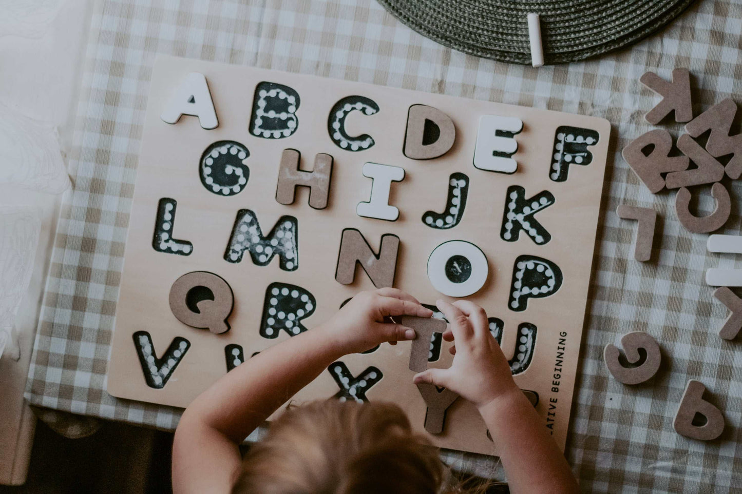Child playing with educational alphabetical puzzle on chalkboard base with tracers promoting fine motor skills and printing accuracy