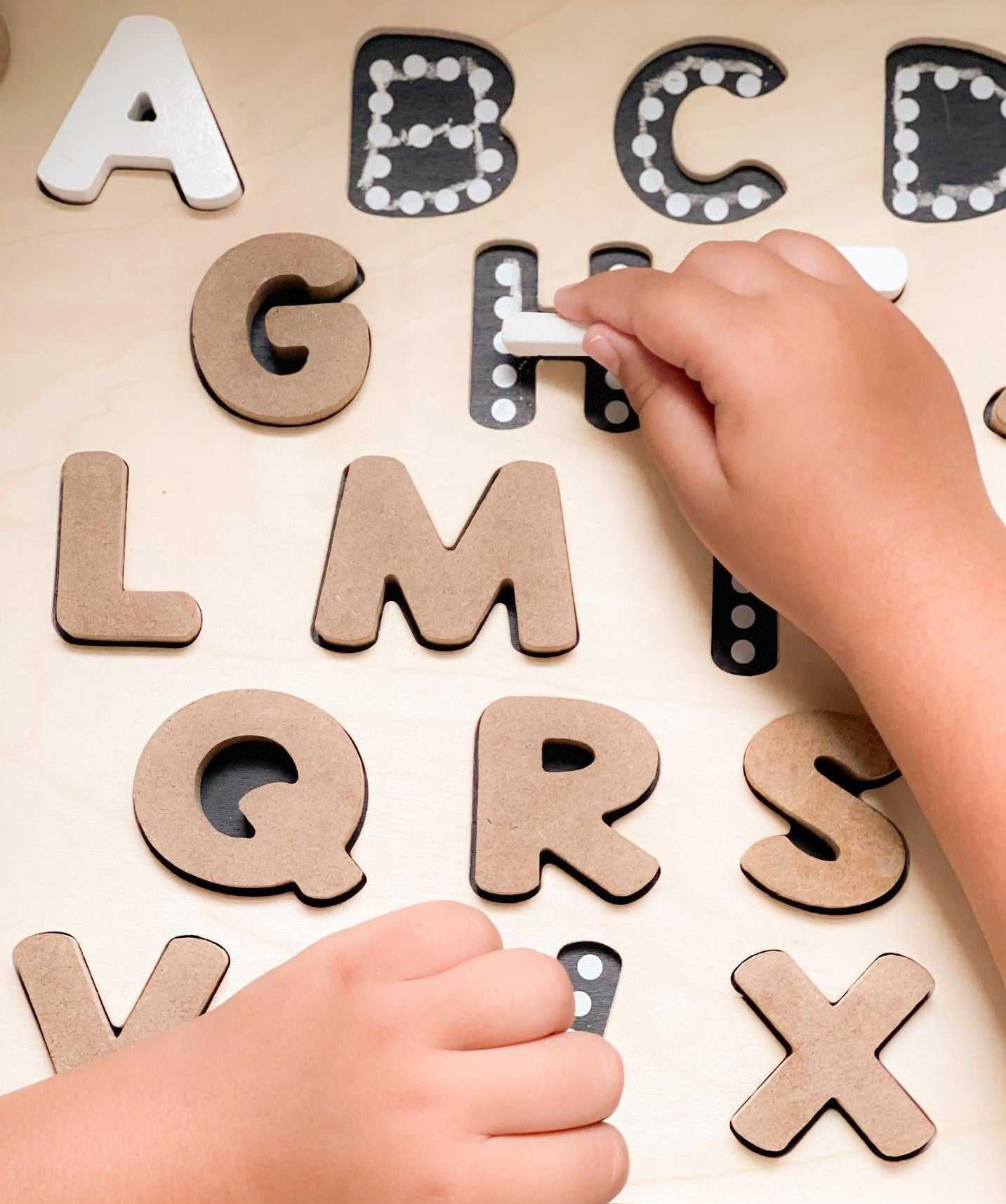 Child tracing alphabet letters on a chalkboard base with tracers educational puzzle