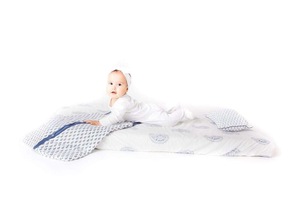 Baby lying on bed wearing lightweight FORT Wearable Baby Sleep Bag made of organic cotton with shoulder snap and zipper closure